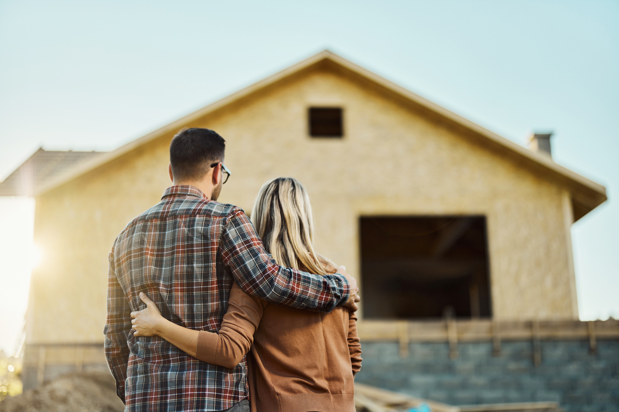 couple heureux devant maison construction