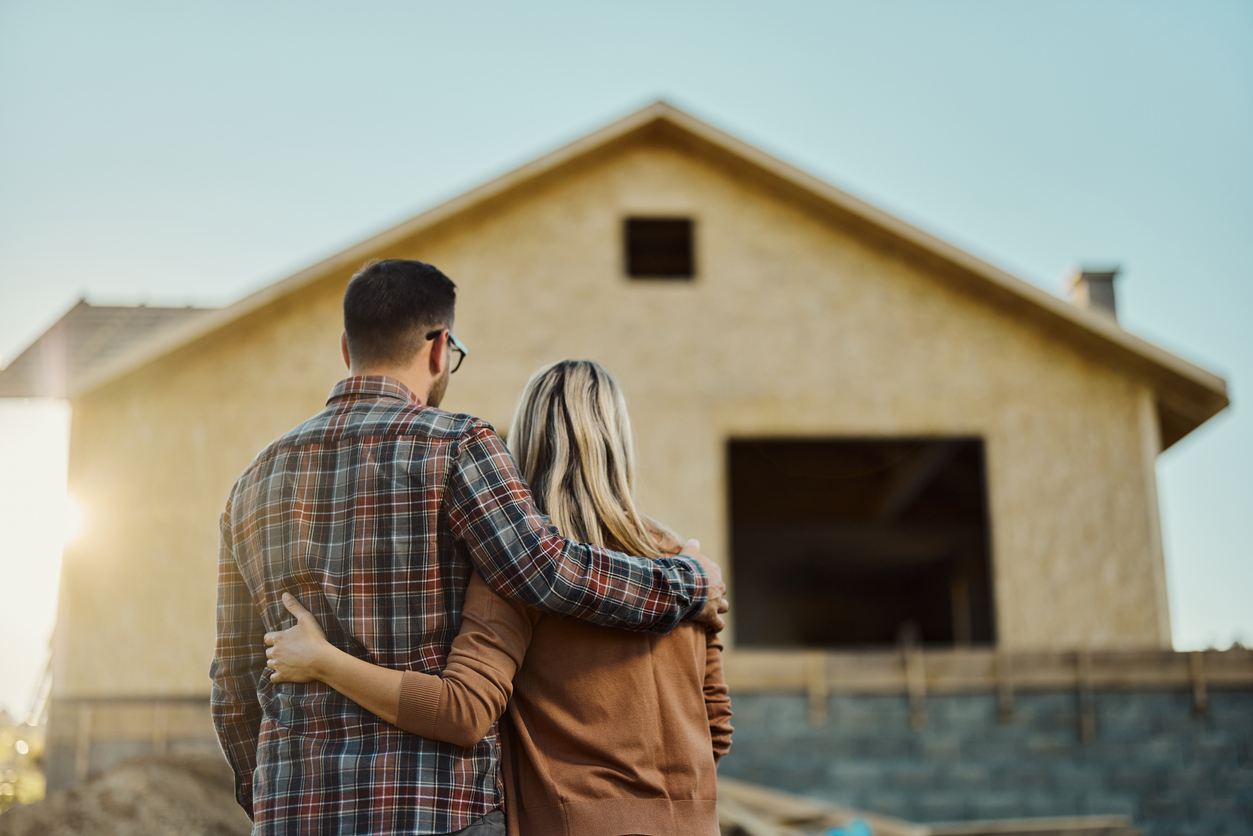 vue d'un couple de dos regardant leur maison en construction