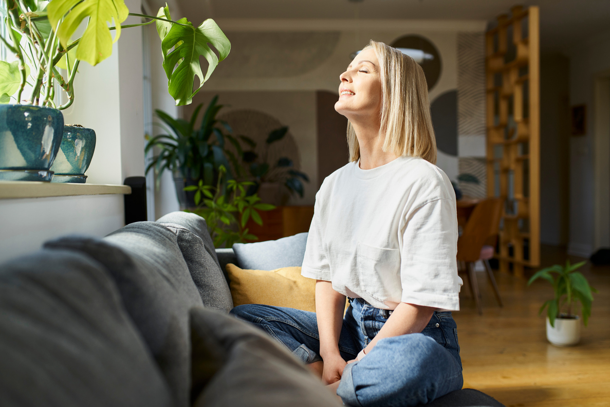 femme assise en face de sa fenêtre profitant de la lumière du jour
